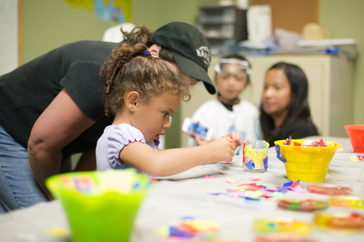 little girl creating caft project with adult helper beside her